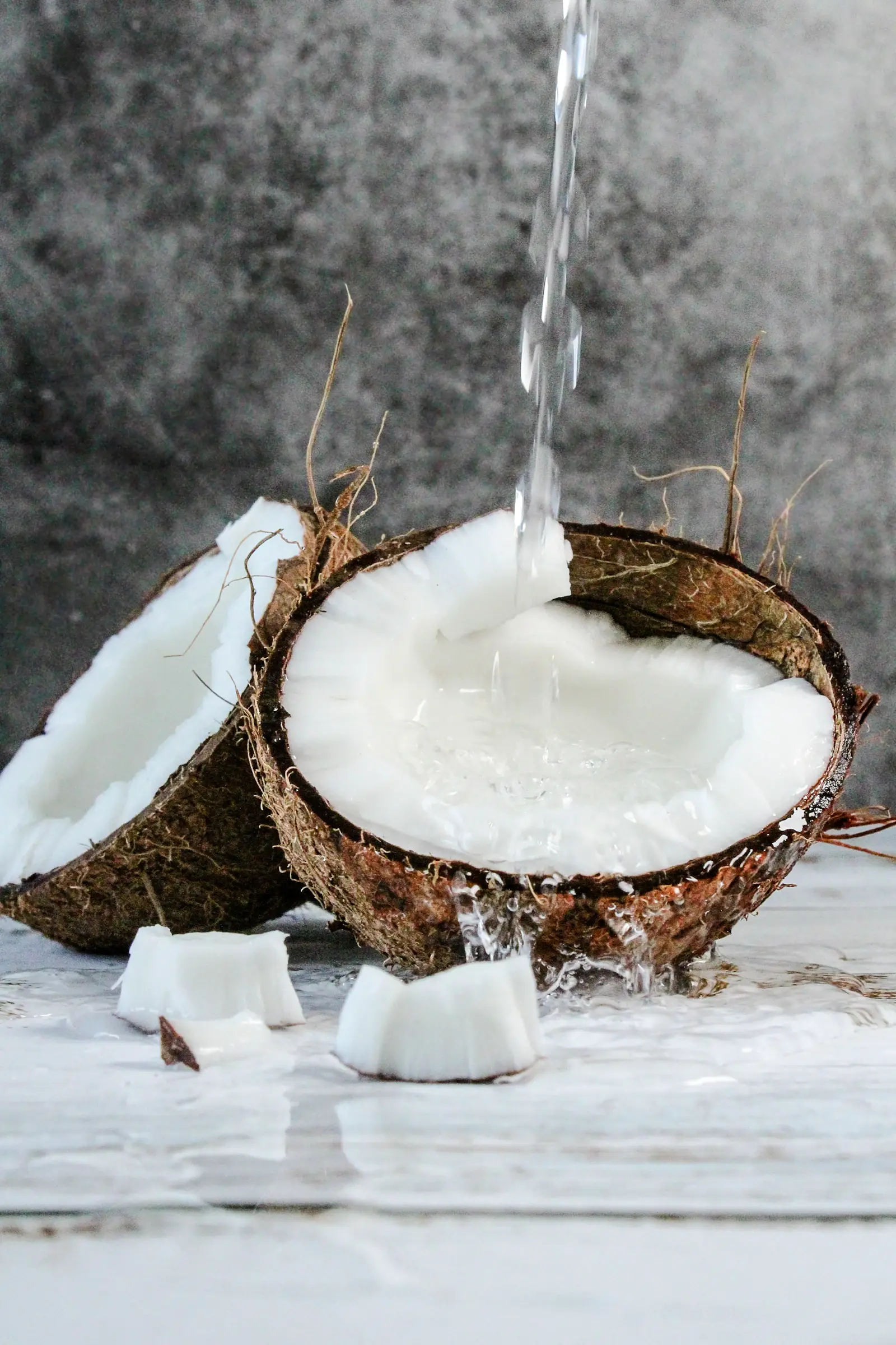 Coconut milk poured beside a split coconut